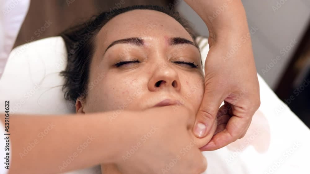 Woman receiving facial massage in beauty salon.Beauty and skincare concept with a beautiful woman. Middle aged female relaxed with massage for facial lifting Woman receiving facial massage in beauty salon.Beauty and skincare concept with a beautiful woman. Middle aged female relaxed with massage for facial lifting