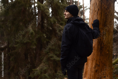 man standing by a tree in the forest