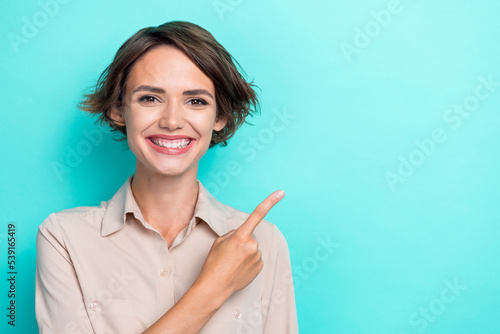 Closeup portrait photo woman office worker toothy beaming smile recommend new whitening clinic finger point empty space isolated on cyan color background