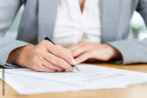Close-up shot of businesswoman filling out insurance policy in her office
