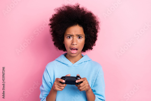 Photo portrait of charming little girl disappointed hold joystick lose game wear trendy blue garment isolated on pink color background