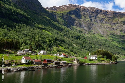 Bakka village with small houses in Norway next to a lake with trees and a river in the background photo