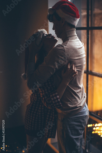 Romantic couple in love feel happiness from their romance while spending Christmas together, woman and man enjoying perfect relationship in cozy home interior. High quality photo