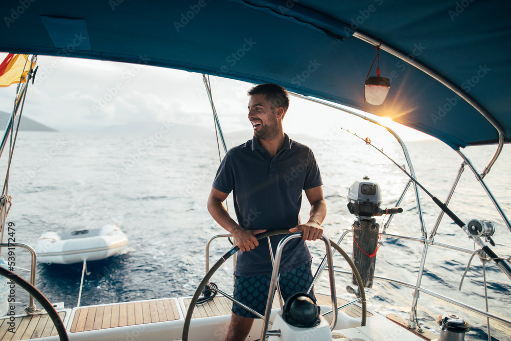 Smiling skipper sailing on yacht, copy space - obrazy, fototapety, plakaty 