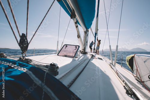 Two men pulling the rope, setting up sails on sailboat © yossarian6