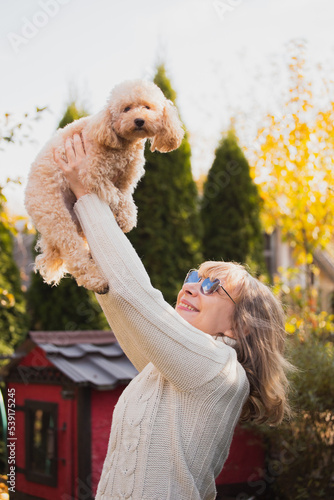 Wallpaper Mural A blonde girl joyfully throws up a cute toy poodle puppy on her arm - love and friendship between a man and a dog Torontodigital.ca