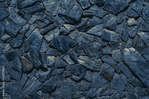 Stone masonry wall, rough layered black sandstone, uneven grungy vintage background close-up, grunge texture
