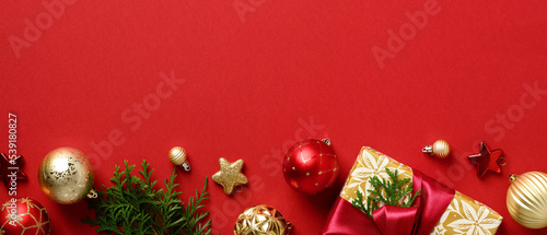 Christmas banner design. Row of Xmas decorations  gold and red baubles  fir branches  gift box on red background. Christmas header template.