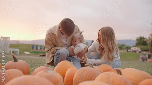 Happy young family at pumpkin patch, smiling and giggling