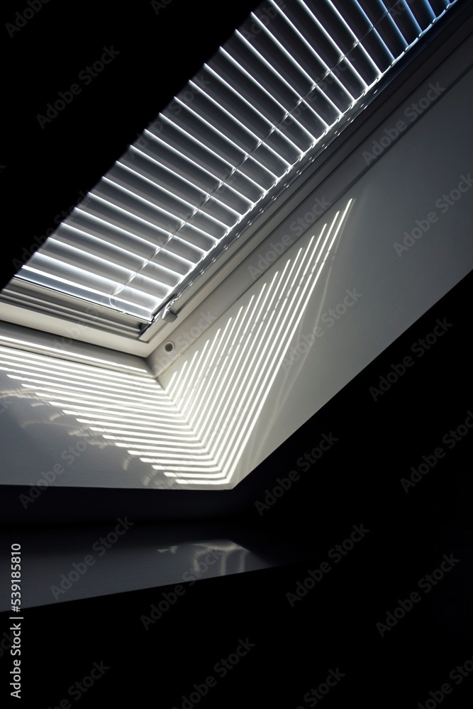 A side portrait of a velux roof window with a closed jalousie in it to keep the sun and warmth out or to keep the light from entering the room in the morning when people are still trying to sleep.