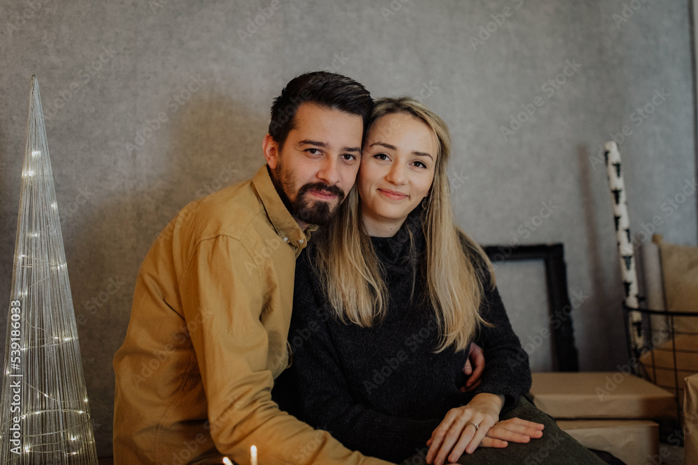 A young couple visibly in love offer each other moments of tenderness in a Christmas decoration with lights and ornaments A young couple visibly in love offer each other moments of tenderness in a Christmas decoration with lights and ornaments