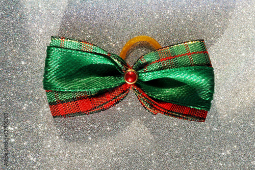 a Christmas green and red bow lies on a silver shiny background.  view from above.  accessory.  preparing for Christmas photo