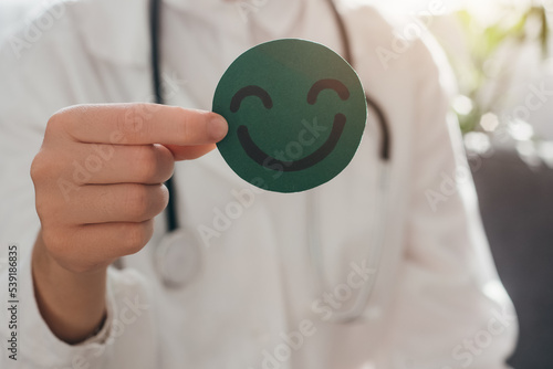 Close up of professional doctor female in coat and stethoscope holding small green happy smiley, satisfaction survey, mental health assessment, child wellness, world mental health day, Compliment Day