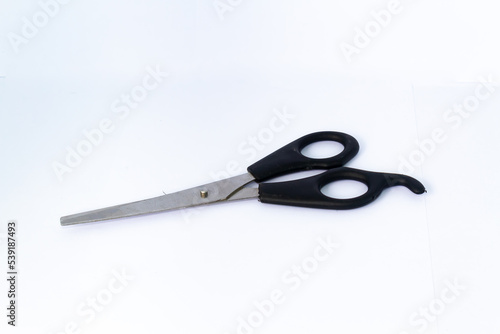 One pair of scissors with a black handle. Used for haircuts. Isolated on white background