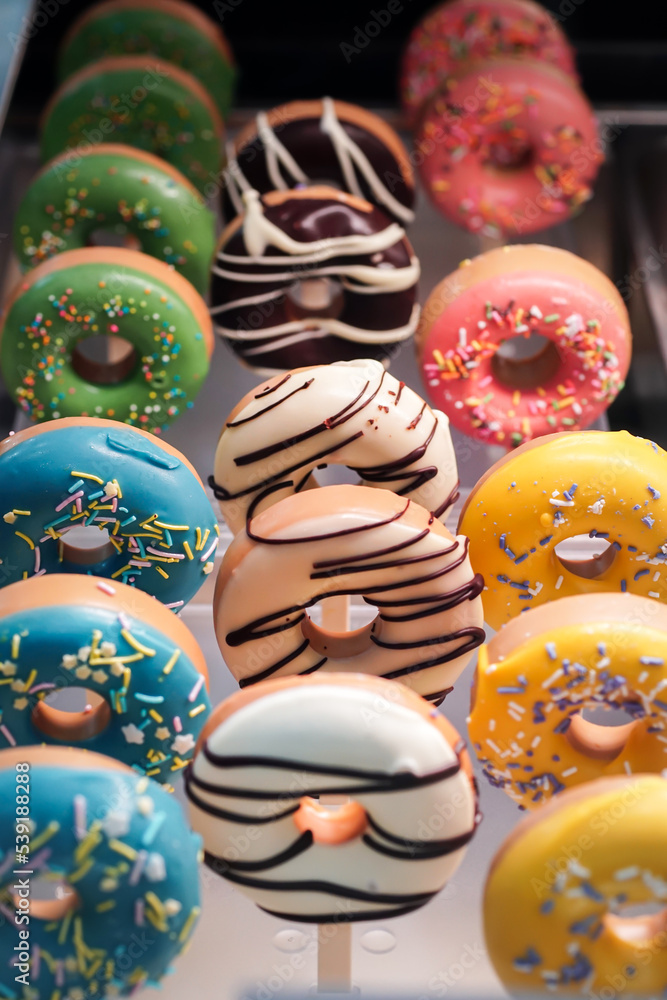 assorted donuts with chocolate frosted, light blue, yellow glazed and sprinkles donuts. carnival concept with sugar.	