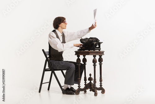 Obraz na plátne Handsome young hipster businessman thinking and writing with vintage typewriter