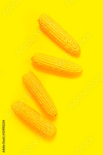 Color Veggies. corn background. Close-up of fresh corn on the cob on a yellow background. The texture of corn. Bright summer background, with summer vegetables and rhythm in the frame. stylish