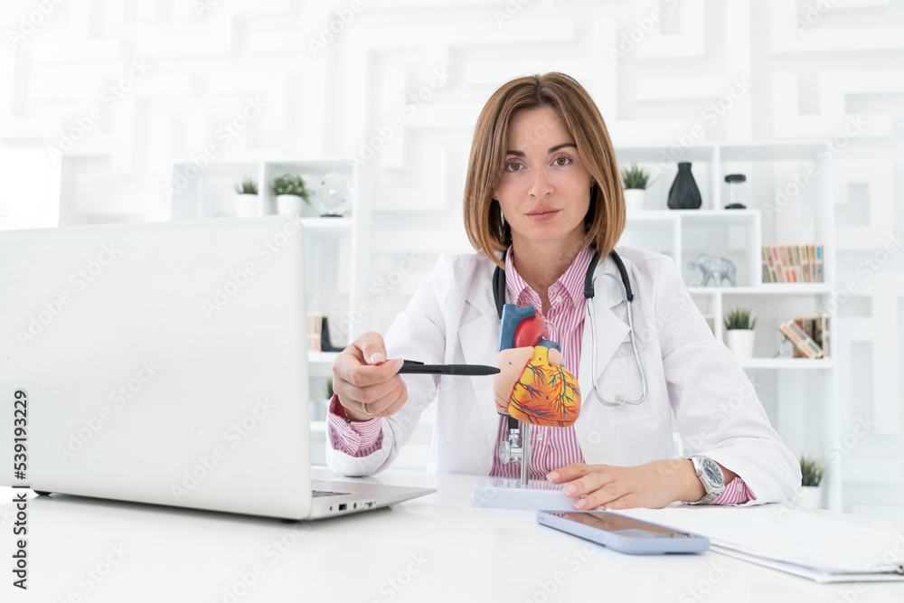 Portrait of young female doctor cardiologist working in office of modern clinic Portrait of young female doctor cardiologist working in office of modern clinic