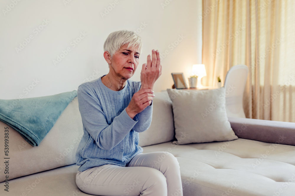 Photo of elderly lady is enduring strong ache while sitting on the sofa during the day. Senior woman at home suffering with arthritis. Upset stressed mature middle-aged woman feeling pain ache. Photo of elderly lady is enduring strong ache while sitting on the sofa during the day. Senior woman at home suffering with arthritis. Upset stressed mature middle-aged woman feeling pain ache.