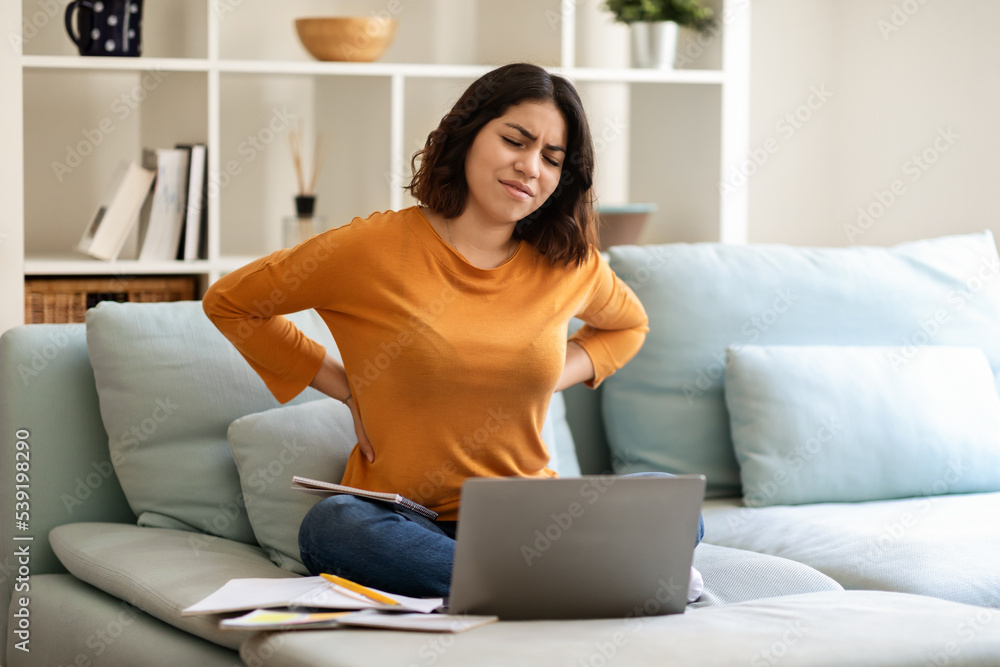 Young Arab Woman Suffering From Backache While Study With Laptop At Home Young Arab Woman Suffering From Backache While Study With Laptop At Home