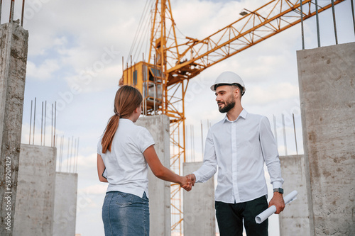 Doing handshake. Successful agreement. Man in uniform working with woman on the construction site