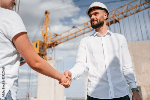 Doing handshake. Successful agreement. Man in uniform working with woman on the construction site