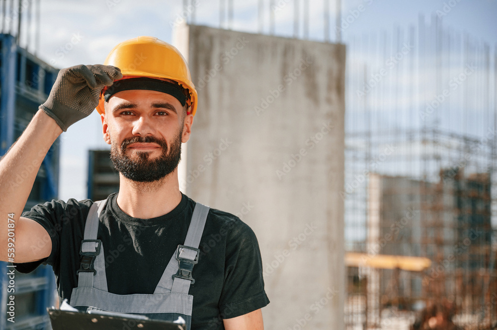 Posing for a camera, with notepad. Beautiful portrait. Man in uniform is working on the construction site Posing for a camera, with notepad. Beautiful portrait. Man in uniform is working on the construction site