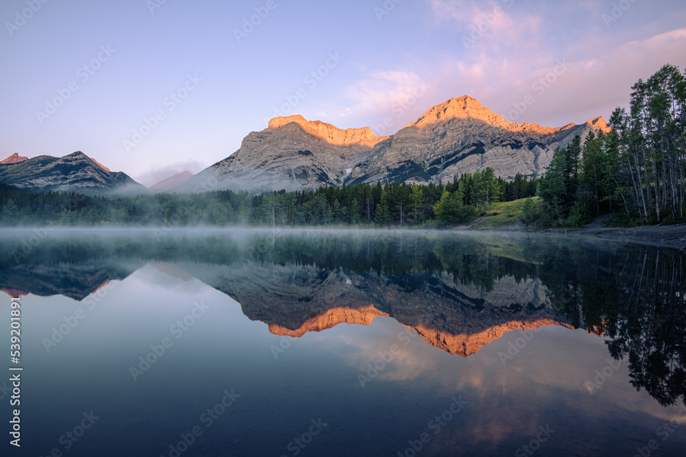 Sun hitting the mountain peaks as the sun rises at Wedge Pond, Canadian Rockies