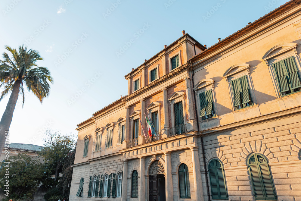 Obraz premium Beautiful old vintage building with a palm tree at sunset in Italy