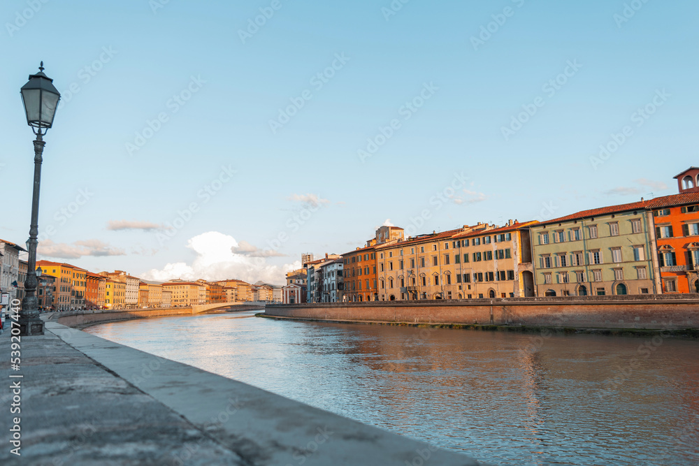 Amazing cozy old European town with vintage buildings along the river with bridges at sunset in Pisa, Italy