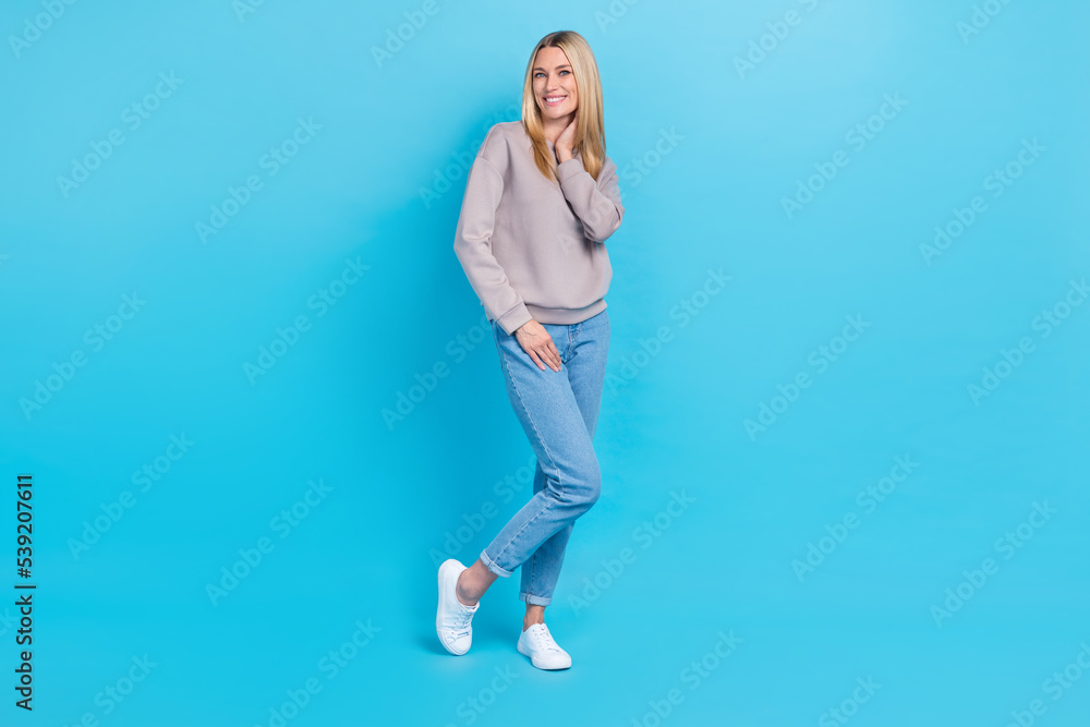 Full length photo of adorable lovely girl dressed grey sweatshirt smiling walking isolated blue color background