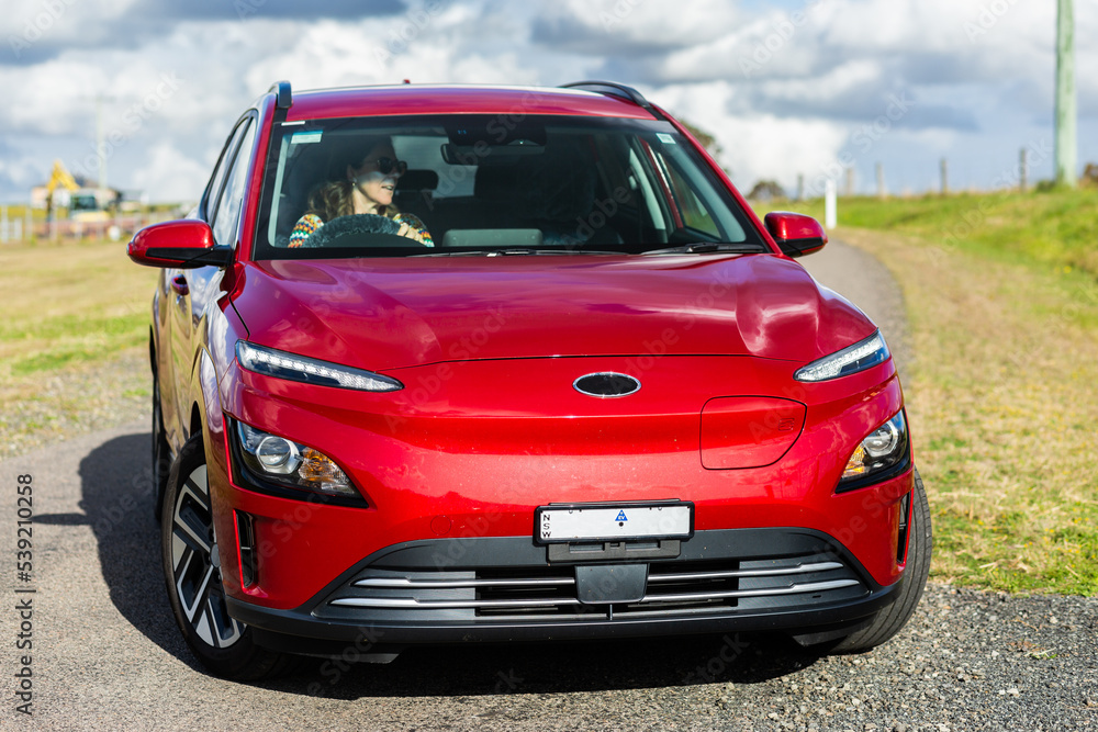Woman driving ev car turning into rural driveway Woman driving ev car turning into rural driveway
