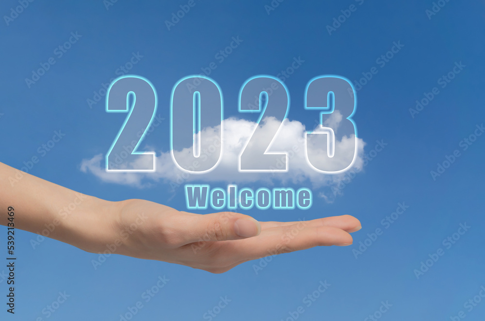 Concept of new year 2023. Woman's hand on background of sky with cloud holds numbers two thousand twenty-three. Welcome to new world Concept of new year 2023. Woman's hand on background of sky with cloud holds numbers two thousand twenty-three. Welcome to new world
