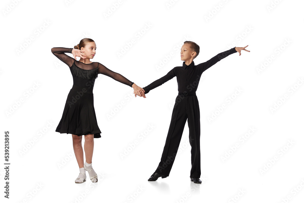 Dance couple. Two kids, school age girl and boy in black stage costumes dancing ballroom dance isolated on white background. Motion, action, hobbies Dance couple. Two kids, school age girl and boy in black stage costumes dancing ballroom dance isolated on white background. Motion, action, hobbies