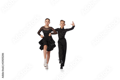 Dance couple. Two kids, school age girl and boy in black stage costumes dancing ballroom dance isolated on white background. Motion, action, hobbies