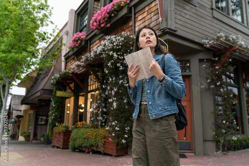 confused asian Taiwanese girl tourist looking around at the street corner in Carmel by the sea with a travel guide book in hand. she has no idea which way to go © PR Image Factory