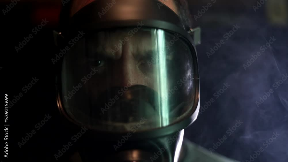 Man in gas mask among poison smoke on dark background. Close up. Man in gas mask among poison smoke on dark background. Close up.