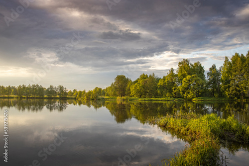 Dawn on the river. the sun's rays illuminate the trees and the pond in the early morning. © Sergei