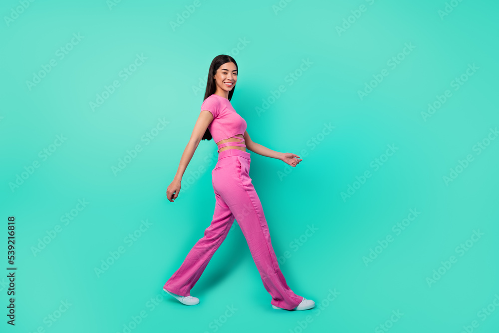 Full length profile side photo of adorable lady go stroll have weekend promenade isolated aquamarine color background Full length profile side photo of adorable lady go stroll have weekend promenade isolated aquamarine color background