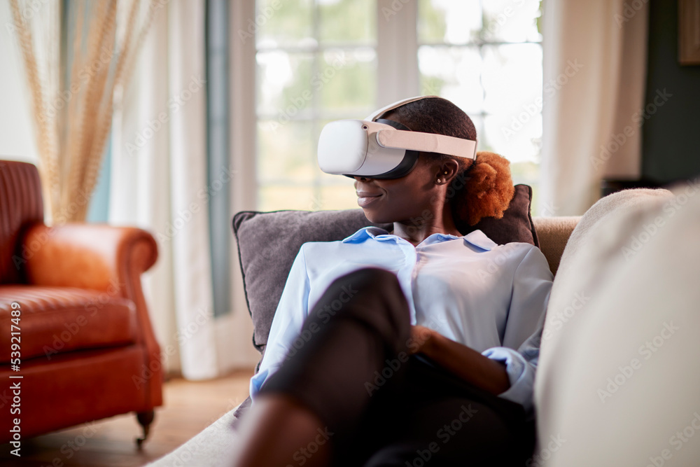 Woman Relaxing Lying On Sofa At Home Wearing VR Headset And Interacting With AR Technology Woman Relaxing Lying On Sofa At Home Wearing VR Headset And Interacting With AR Technology