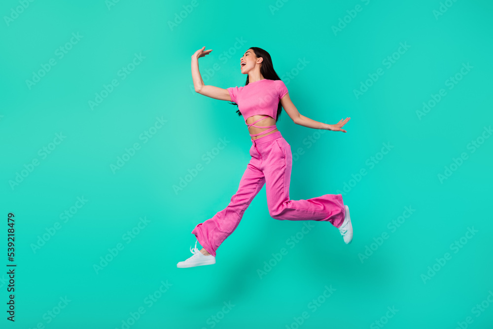 Full length profile side photo of active energetic female feel free jumping up isolated on teal color background