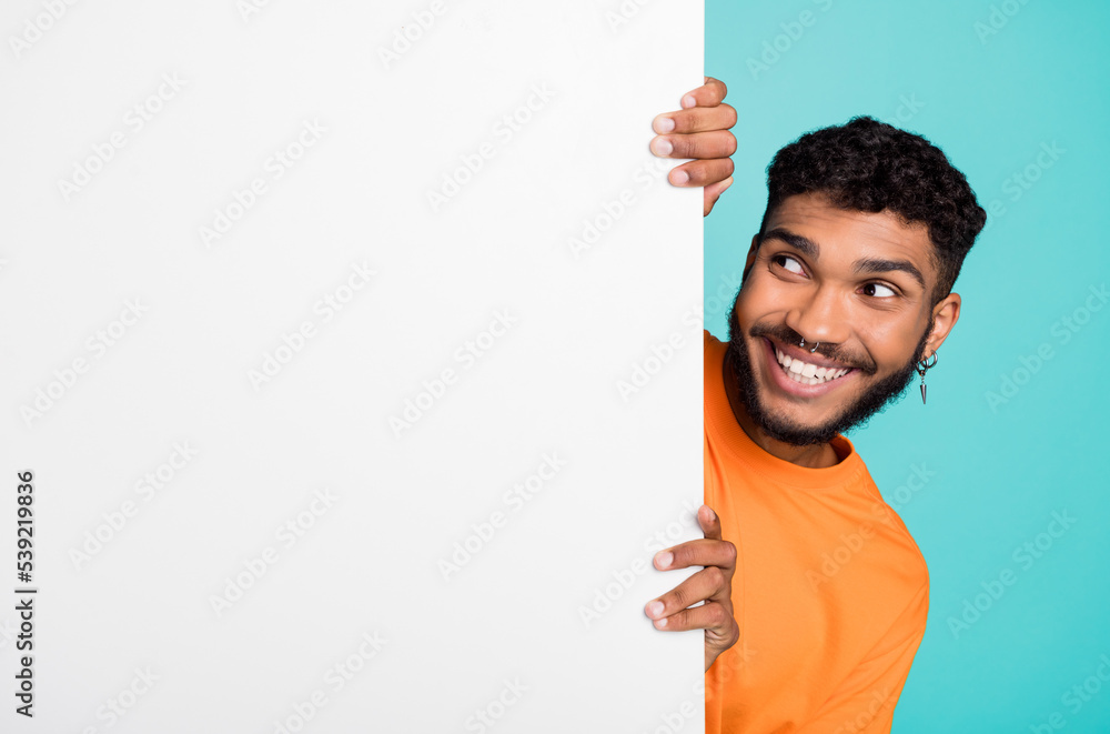 Photo of cheerful person look interested empty space beaming smile isolated on teal color background Photo of cheerful person look interested empty space beaming smile isolated on teal color background
