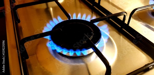 Close-up of blue fire over the home kitchen stove. Gas stove with flames burning propane gas. Industrial resources and economy concept.
