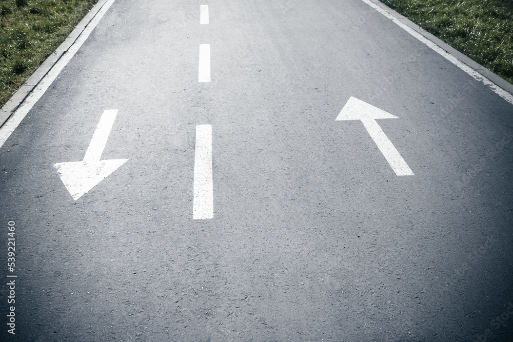 Two white arrow signs on opposite direction on asphalt road. Both sides sign. Up and Down arrows. Direction for traffic safety way. Pointer on gray asphalt floor.