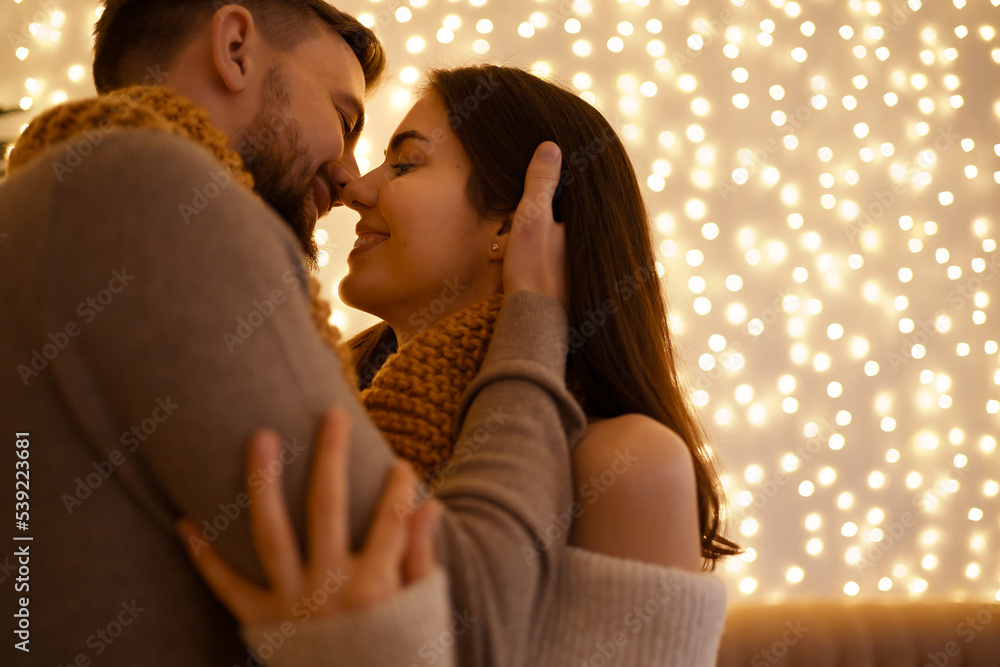 Two lovely sweet tender beautiful adorable cute romantic couple enfolding in one snood celebrating love and kissing on lights background