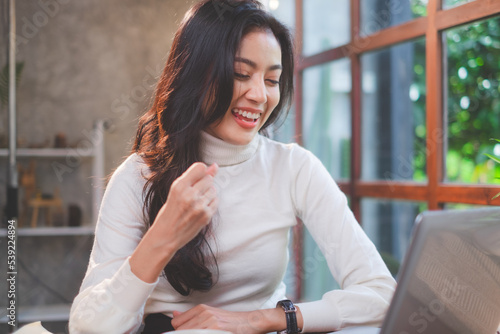 Female freelance is happy and cheerful for work while using notebook or laptop to video conference in coffee shop. Female entrepreneur working in cafes. Cyberspace and workspace.