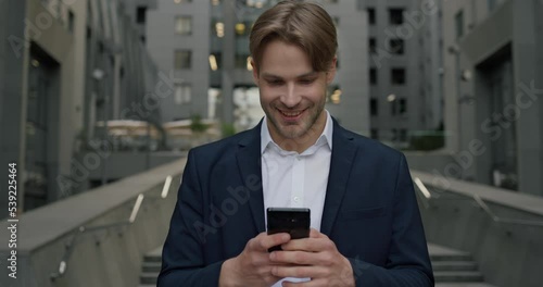 Smiling man in formal suit uses smartphone and chatting online in apps photo