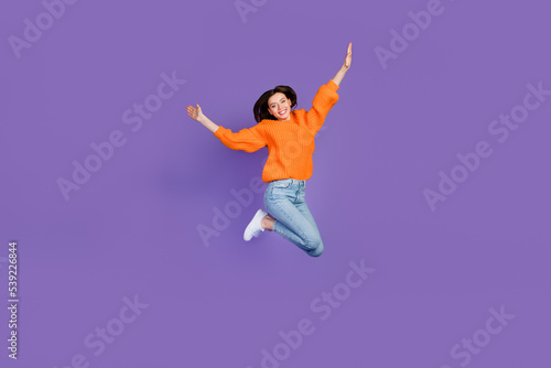 Full length photo of adorable young lady jumping high sportive wear trendy orange knitwear clothes isolated on violet color background