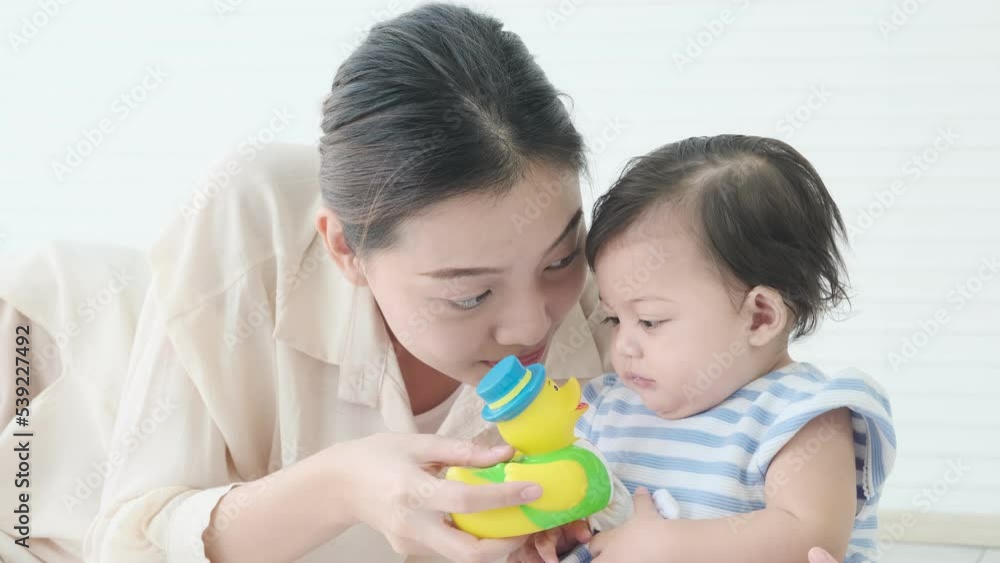 Baby little girl playing with her mother who holding rubber duck toy joking with her. Baby little girl playing with her mother who holding rubber duck toy joking with her.