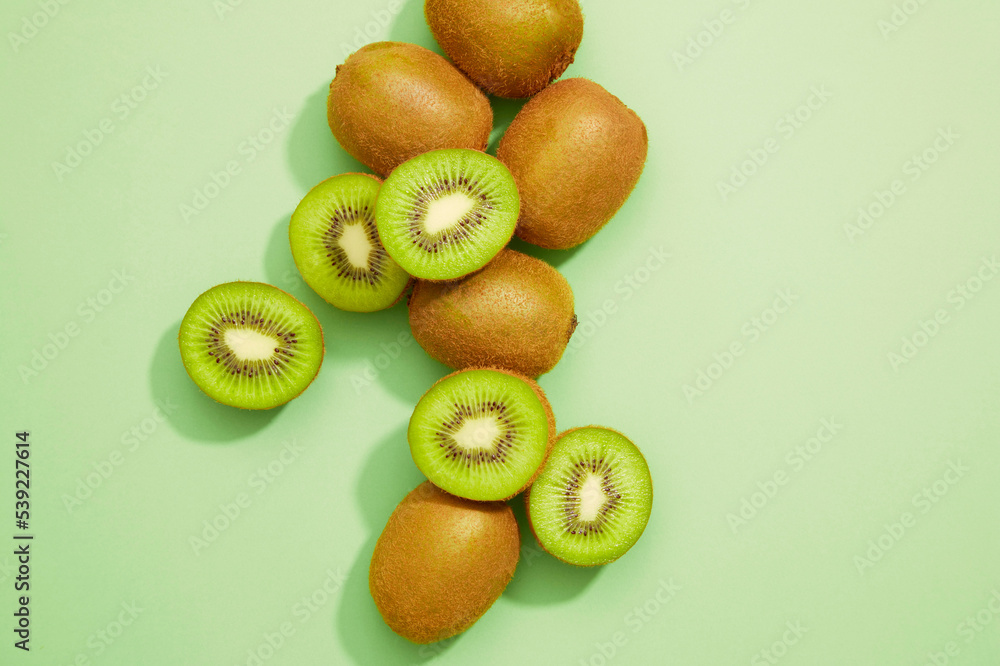 Obraz premium Fresh kiwi with a slice fruit on a green background. Summer weather, green living, healthy life